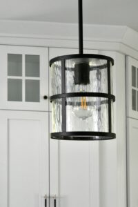 Matte black and water glass combined with decorative edison bulbs strike the right balance in this luxurious but casual kitchen.